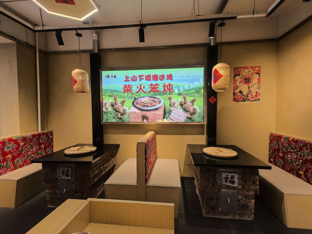 曲府粮满仓柴火铁锅炖中央大街店实拍 - 双灶卡座区实拍：灶口贴「福」字，竹编灯笼配东北大花布靠背